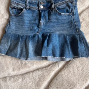 Blå jeanskjol med volangkant - Säljer en blå jeanskjol med volangkant nertill och råa kanter. Jag har sytt kjolen själv av ett par jeans från Gina tricot. Storlek 158, men passar 32-34