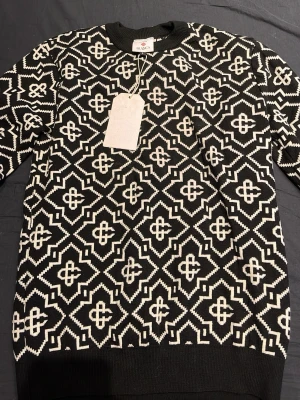 Svartvit mönstrad stickad tröja Casablanca - Säljer en svartvit stickad tröja från Casablanca med grafiskt mönster över hela plagget. Tröjan har rund halsringning, långa ärmar och ribbade muddar. Perfekt för dig som gillar statement-plagg och vill sticka ut lite extra.