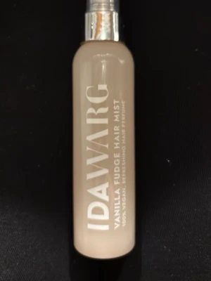 IDA WARG Vanilla Fudge Hair Mist - Fräsch hårmist från IDA WARG med doft av vanilla fudge. Kommer i en beige plastflaska med silvrig spraypump. 100% vegansk och fungerar som en uppfriskande hårparfym. Perfekt för att ge håret en söt och fräsch doft. Typ 1/3 kvar!