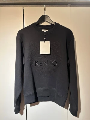 Kenzo Sweatshirt  - Svart sweatshirt från Kenzo i storlek XS. HELT OANVÄND, lappar sitter kvar. Lite större i storleken passar S.