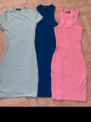 Tre ribbade klänningar i olika färger - Säljer tre snygga ribbade klänningar från I AM i storlek S. En ljusblå med kort ärm, en marinblå ärmlös och en rosa ärmlös. Alla har en kroppsnära passform och är gjorda i mjuk bomull. Perfekt för dig som gillar stilrena och färgglada outfits.