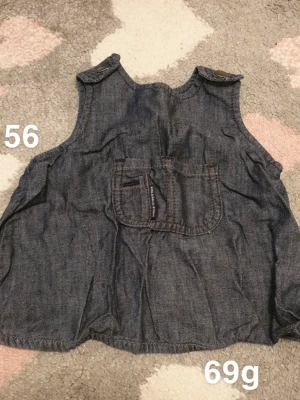 Mörk jeansklänning från Polarn O. Pyret - Söt mörk jeansklänning från Polarn O. Pyret i storlek 56. Klänningen har en praktisk ficka framtill och knappar på axlarna för enkel påklädning. Perfekt till sommaren och enkel att matcha med andra plagg.🌸 Fint använt skick. Storlek 56