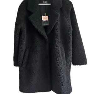 Svart oversize teddyjacka. ONLY Petite  - Svart Oversize teddyjacka från ONLY Petite med klassisk krage och knäppning framtill. Jackan är av ett fluffigt teddy-material som håller dig varm. Oversize var helt enkelt inte min grej. Helt nu med prislapp kvar. 