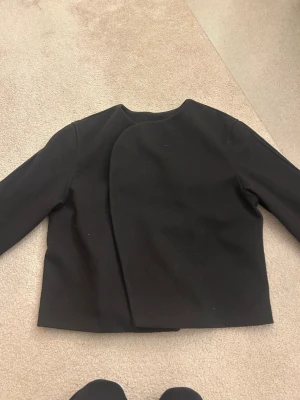 Super fin svart kappa - Super fin svart kappa som aldrig använts. Storlek S men skulle säga att den passar både xs och m också beroende på hur man vill att den ska sitta! Tvättas självklart innan den skickas om köpare vill de! 