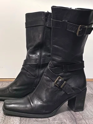 Svarta stövlar i skinn - Stövlar i svart skinn, ofodrade, dragkedja på insidan. Är i  storlek 40, men stora, så 41 skulle jag säga. Väldigt lite använda. Omsulade och omklackade direkt efter att de köptes. 