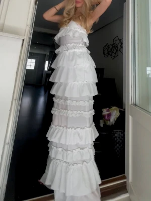 Vit långklänning med volanger - Lång klänning som passar perfekt för midsommar! Använde förra året och fick så många komplimanger🥹 endast använd en gång! Nypris 1400kr
