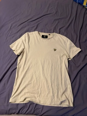  Lyle & Scott XL - Säljer en stilren  t-shirt från Lyle & Scott i storlek XL. T-shirten har klassisk rund hals och korta ärmar, med den ikoniska gula fågeln broderad på bröstet. Materialet är mjuk bomull som känns skön mot huden. Perfekt för dig som gillar enkel och snygg design.