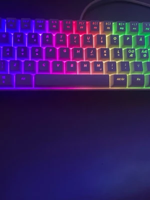 MX5 Mini Keyboard RGB - Snygg MX5 Mini Keyboard med RGB-belysning som ger tangentbordet ett färgstarkt utseende. Kompakt design, nordisk layout och USB-anslutning. Tangenter och belysning ser ut att vara i mycket gott skick utan synligt slitage. Perfekt för gaming eller kontorsbruk.