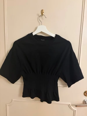 Svart topp med ribbad midja - Svart topp med insydd midja från Gina Tricot. Storlek Xs