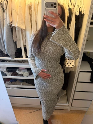 Stickad långklänning med öppen rygg - Stickad långklänning som är öppen i ryggen i storlek xs/s. Klänningen har lång ärm med lätt utsvängda ärmslut och en kroppsnära passform. Löpt för 700kr