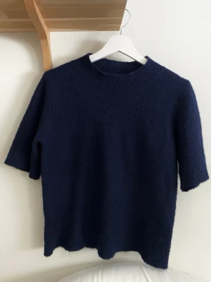 Mörkblå stickad t-shirt - Mysig mörkblå stickad tröja från By Swan Paris. Upplever att den har blivit lite nopprig men inget jag har försökt göra något åt. Onesize men skulle säga ungefär storlek S. 