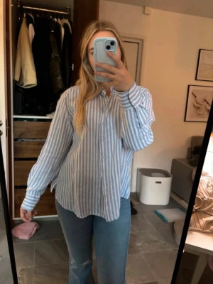 Blåvit randig skjorta från Stories - Säljer en snygg blåvit randig skjorta från Stories i storlek M. Skjortan har klassisk krage, knäppning framtill och långa ärmar. Perfekt för en chill och stilren look. Gjord i ett lätt och skönt bomullsmaterial.