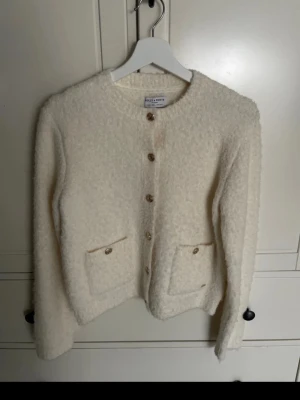 Vit kofta  - Mysig vit kofta köpt från Lindex och märket Holly & Whyte. Koftan har guldfärgade knappar framtill och två fickor med knappdetaljer. Långärmad och rundad halsringning