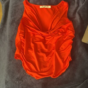 Röd omlott linnetopp från NA-KD - Säljer en snygg röd omlott linnetopp från NA-KD i storlek S. Toppen har draperad front och är ärmlös med rundad nederkant. Materialet är mjukt och glansigt. Perfekt till fest, sommar eller utekväll!❤️ Mycket bra skick 