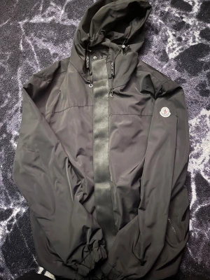 Svart vindjacka från Moncler - Svart vindjacka från Moncler med huva säljer denna lite stor för mej hör av er tar emot byte oxå såklart HÄMTAS I BORÅS