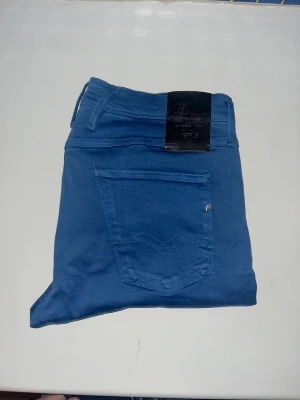 Replay Anbass jeans  - Säljer ett par blå Replay Anbass jeans i slim fit-modell. Materialet är mjukt och stretchigt för extra komfort. OBS uppsyd för att motsvara L32 men utgå från måtten. Midja 43cm, längd 99cm.  JAG SKICKAR EJ FLER BILDER NÄR JAG BÄR JEANSEN! för storleksguide hänvisar jag till måtten och för bättre inblick i passformen rekommenderar jag att googla på modellnamnet. kolla måtten noggrant :) 67