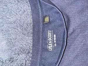 Mörkblå t-shirt från Lyle & Scott - Snygg mörkblå t-shirt från Lyle & Scott med klassisk gul fågel-logga på bröstet. T-shirten har rund hals och korta ärmar, perfekt för en chill och stilren look. Materialet är mjukt och skönt bomullstyg som passar året runt.