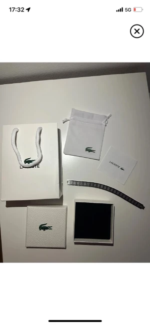 Lacoste armband i rostfritt stål - Snyggt armband från Lacoste i silverfärgat rostfritt stål med länkdesign och ingraverad Lacoste-logga. Kommer med original ask, påse och certifikat. Perfekt accessoar för dig som gillar stilrena detaljer och ikoniska märken.