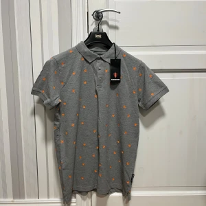 Grå pikétröja från Koenigsegg storlek M - Grå pikétröja från koenigsegg storlek M helt ny med prislapp aldrig använd.