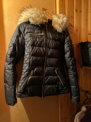 ROCKANDBLUE JACKA kort - Säljer då den är lite för stor för mig och aldrig kommer till användning! Stl. 36 i fint skick! Svart/mörkblå med guldiga dragkedjor. Luvan är avtagbar och går att tvätta om man vill! Kostade 2995kr när jag köpte den ny! Lämna gärna prisförslag om priset inte passar! :)