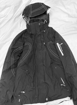 Skidjacka Peak Performance  - Snygg skidjacka med snölås på insidan från Peak Performance svart med vita detaljer , Goretex. Storlek L/40. Använd bara få gånger men åker inte skidor längre. 