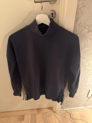 Mörkblå sweatshirt från SOC XS - Mörkblå sweatshirt från SOC i storlek XS. Tröjan har långärmad design, hög krage med liten öppning framtill och ribbade muddar vid ärmslut. Materialet är mjukt och känns som bomull eller polyester. Perfekt för chill dagar eller träning.