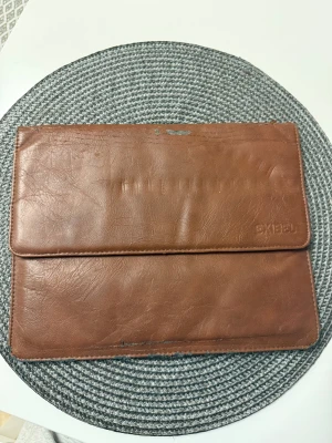 iPad fodral - Snygg brun iPad fodral från Exibel i äkta skinn. Stilren och enkel design med slät yta och praktiskt magnetlock. Insidan är ljusgrå och har ett stort fack för iPad eller dokument. Perfekt för dig som gillar minimalistisk stil.