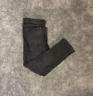 Svarta slim jeans från Jack & Jones  - Säljer ett par svarta jeans från Jack & Jonss med klassisk femficksdesign och slim passform. Jeansen är tillverkade i mjukt bomullsmaterial med stretch för extra komfort. Perfekta för dig som gillar stilrena och moderna jeans.          Längd: 30, midja: 31. Pris går att diskutera. Hör gärna av dig vid frågor.