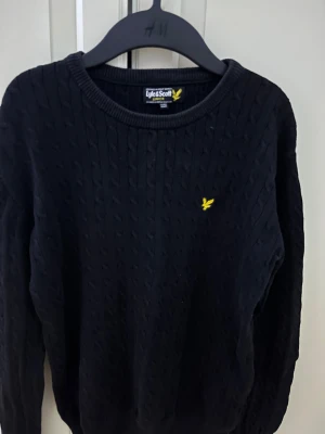 Svart Lyle  & Scott stickad  - Svart Lyle  & Scott stickad. Den är i storlek 12-13yr, och passar om du är runt 155-165 cm lång. Den är i utmärtskick och kostar ungefär 500kr ny