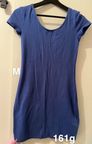 Blå kortklänning med rund hals - En enkel och snygg blå kortklänning med rundad halsringning och korta ärmar. Klänningen har en slim passform som sitter skönt mot kroppen. Perfekt för dig som gillar stilrena och bekväma plagg.🌸 Fint använt skick. Storlek m