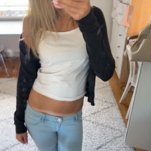 Svart kofta med knappar, långärmad - En svart, klassisk kofta med v-ringning och knappar framtill. Långärmad modell i mjukt material, perfekt att slänga över en topp. Ribbstickade muddar vid ärmslut och nederkant ger en snygg passform. 