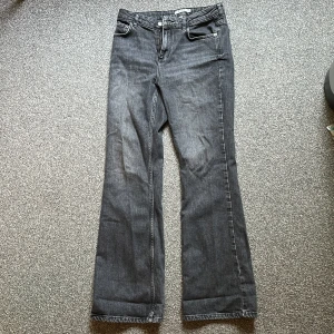 Grå bootcut jeans från NA-KD - Snygga grå jeans från NA-KD i bootcut-modell. Jeansen har klassisk femficksdesign, bälteshällor och dragkedja med knapp. Materialet är jeans med en tvättad grå finish som ger en cool vibe. Eftersom jag är 1.62 har jag skrapat byxorna nere! Så de är ett hål där nere på byxan! Skulle säga att dessa byxor passar för dig som är 168 och längre! 