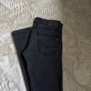Replay svarta jeans slim fit - Svarta jeans från Replay med klassisk femficksdesign och snygga detaljer på bakfickorna. Jeansen har en slim passform och är tillverkade i ett stretchigt bomullsmaterial för extra komfort. Perfekta för dig som gillar en stilren och modern look. Storlek w33