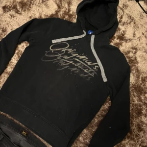Jack and Jones holdie  - Säljer en svart hoodie med trycket 'Originals' framtill och gråa snören i luvan. Tröjan har en klassisk passform och är perfekt för en avslappnad stil. Mjuk insida och ribbade muddar vid ärmslut och nederkant. Pris kan diskuteras vid snabb affär 
