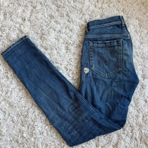 Blå jeans från Dondup - Säljer ett par blåa dondup George jeans med slitna detaljer. Jeansen har en lagning mellan bena därav det lägre priset, men defekten syns inte när jeansen är på. 