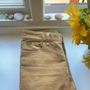 Beiga manchesterbyxor Polo Ralph Lauren - Säljer ett par snygga moccabruna manchesterbyxor från Polo Ralph Lauren. Byxorna har klassisk femficksdesign, bälteshällor och är tillverkade i mjuk manchester. Perfekta för dig som gillar en stilren och avslappnad look. Använda och tvättade en gång. Nypris -1695kr