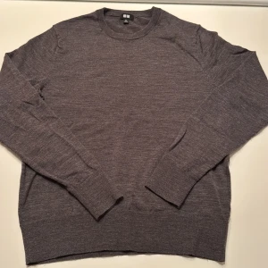 Grå stickad tröja från Uniqlo XS - En stilren grå stickad tröja från Uniqlo i storlek XS. Tröjan har rund halsringning, långa ärmar och ribbade muddar vid ärmslut och nederkant. Perfekt för lager-på-lager och enkel att matcha med jeans eller kjol.