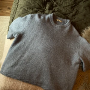 Ljusgrå stickad tröja Gina Tricot - Supermjuk ljusgrå stickad tröja från Gina Tricot med kort ärm och rund halsringning. Enkel och clean design som är lätt att styla med allt. Perfekt för lager-på-lager och chill dagar.