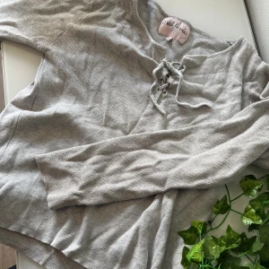 Grå ribbad tröja med snörning - Superskön grå långärmad tröja från C'est la vie (Ullared) med ribbad struktur och snygg snörning vid halsen. Perfekt för dig som gillar en enkel men ändå trendig look. Passar till jeans eller kjol för en chill vibe. 🌸