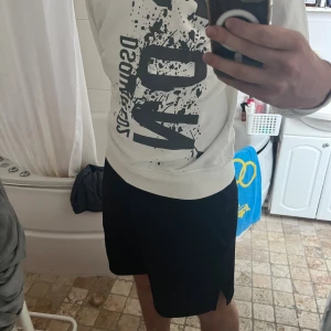 Vit sweatshirt från Dsquared2 ICON - Vit sweatshirt från Dsquared2 med stor svart 'ICON'-print och coolt splattermönster framtill. Tröjan har rund hals, långa ärmar och en relaxed passform. Perfekt för dig som gillar streetstyle och vill sticka ut med en statement-piece.