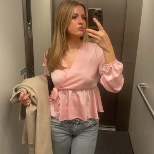 Rosa omlottblus med volang - Säljer en superfin ljusrosa omlottblus med volangkant och knyt i midjan. 