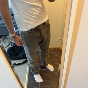 Grå raka jeans i loose fit - Säljer ett par grå jeans med rak passform och loose fit. Jeansen har klassisk femficksdesign och är tillverkade i mjukt denimtyg. Perfekta för dig som gillar en avslappnad och stilren look.