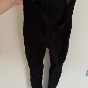 Svarta slim byxor med dragkedja - Svarta byxor med slim passform och dragkedja framtill. De har en klassisk rak design och är tillverkade i ett mjukt bomullsmaterial som sitter skönt mot kroppen. Perfekta för dig som gillar en stilren och enkel look. Dessa byxor är stretchiga och inget jeans material 