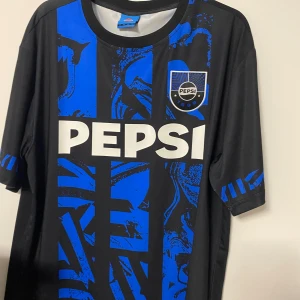 LIMITED EDITION PEPSI fotbollströja -  fotbollströja med PEPSI-logga på bröstet och unikt blått och svart grafiskt mönster. Tröjan har korta ärmar och rund hals. Tillverkad i lätt och ventilerande material, perfekt för match eller träning. Snygga blå detaljer även på ärmarna. LIMITED EDITION! Pris kan diskuteras vid snabbt köp 