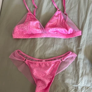 Rosa set med leopardmönster och mesh - Snygg rosa underkläder med leopardmönster och transparenta meshdetaljer på både överdel och underdel. Triangel-bh med justerbara axelband och underdel med meshvingar i sidorna. Överdel st 75b och underdel st S