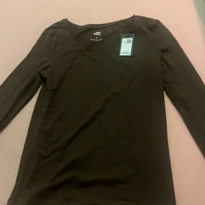 Brun långärmad topp från 157 XS - En basic brun långärmad topp från 157 i storlek XS. Tillverkad i mjuk bomull med lite stretch för en skön passform. Enkel och stilren design med rund halsringning, perfekt att matcha med jeans eller kjol.