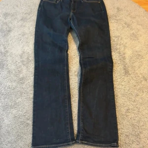 Levi's mörkblå bootcut jeans - Mörkblå jeans från Levi's med klassisk femficksdesign och kontrastsömmar. Modellen har bootcut-ben som ger en snygg siluett och är tillverkad i slitstarkt denim. Perfekta för dig som gillar en tidlös och avslappnad look. Priset kan alltid diskuteras