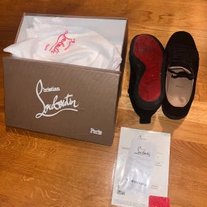 Christian Louboutin svarta sneakers - Svarta sneakers från Christian Louboutin med klassisk röd sula och ovandel i mocka. Kommer med originalkartong, dustbag och äkthetsbevis. Priset är ej hugget i sten 