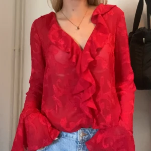 Röd volang-blus - Superfin röd färg och väldigt tunt och luftigt material! Knappar i mitten som döljs superfint av volangerna! Ändats använd en gång så i nyskick!