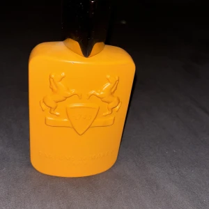 Parfums de Marly Perseus EdP 125ml med 80%kvar i flaskan - Exklusiv parfymflaska i orange från Parfums de Marly, modellen Perseus Eau de Parfum. Flaskan har en stilren, rektangulär form med rundade kanter och ett silverfärgat lock. Embossad logga med två hästar och sköld framtill. Rymmer 125 ml.